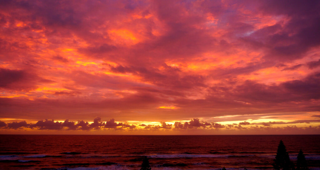 Surfers Paradiseの海岸から見た、紫と紅に染まる夜明けの空と雲